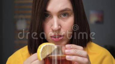 女孩正在<strong>喝红茶</strong>，看着相机。 迷人的年轻女子病了，<strong>喝</strong>柠檬茶。 感冒，流感